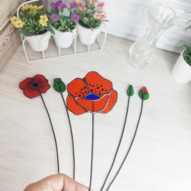 set of flowers and poppy buds made of transparent orange stained glass